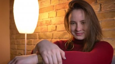 Closeup ateş kameraya bakarak ve rahat bir daire içinde kapalı gülümseyen genç sevimli tombul kadın