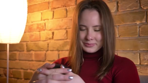 Gros plan portrait de jeune jolie femme caucasienne regardant caméra et souriant séduisante à la maison confortable à l'intérieur — Video