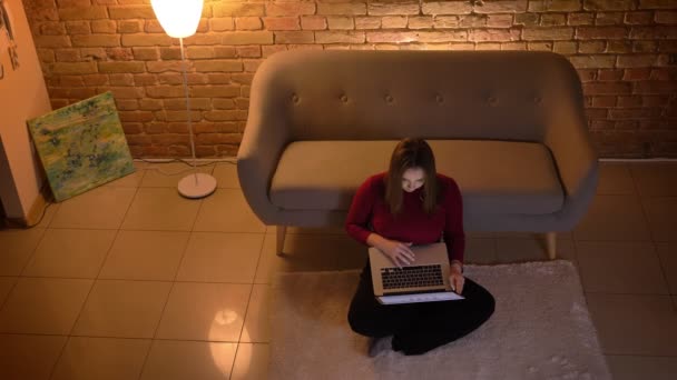 Zbliżenie góry strzelać młodych atrakcyjnych kaukaski kobiece pisanie na laptopie siedząc na podłodze w przytulny apartament — Wideo stockowe