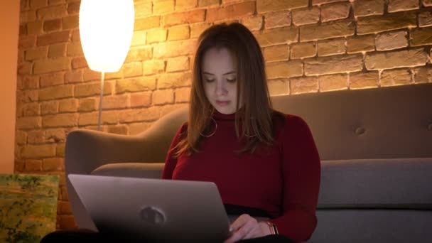 Closeup shoot of young attractive caucasian female using the laptop while sitting on the floor in a cozy apartment — Stock Video