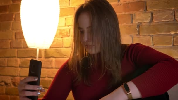 Closeup střílet z mladých modernější ženské s video volání na telefonu v útulném bytě uvnitř — Stock video