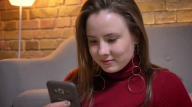 Closeup ateş sonra kameraya bakıyor ve gülümseyerek telefonu kullanarak genç çekici tombul beyaz kadın