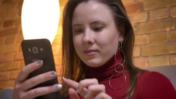 Primer plano shoo9t de jóvenes bastante sobrepeso mujer caucásica utilizando el teléfono en el interior en un acogedor apartamento — Vídeos de Stock