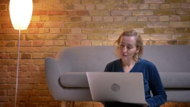 Closeup ateş eldery beyaz kadın kapalı yere oturmak belgili tanımlık laptop üzerinde gösterisi izlemek.