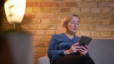 Tablet üzerinde yaşlılar beyaz kadın tarama ve açık kanepede otururken heyecanlı almak closeup ateş