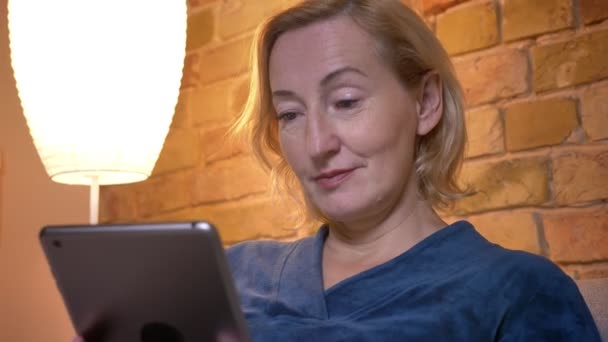 Closeup zastřelí starší kavkazské ženské prohlížení tabletu, pak se dívá na kameru a usmívá se — Stock video