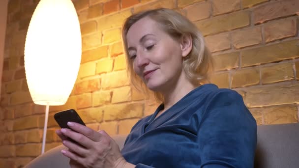 Closeup shoot of eldery caucasian female typing on the phone then looking at camera and smiling — Stock Video