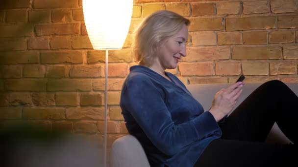 Primo piano ripresa di anziano caucasico femmina utilizzando il telefono e sorridente all'interno — Video Stock