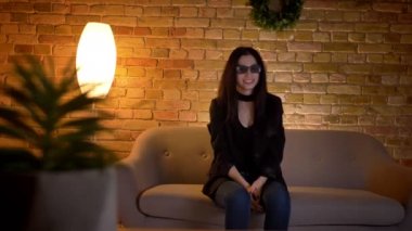 Rahat ev atmosferinde eğlence kanepede gerçekçi film reclines izlerken 3D Gözlük Genç esmer beyaz kız.