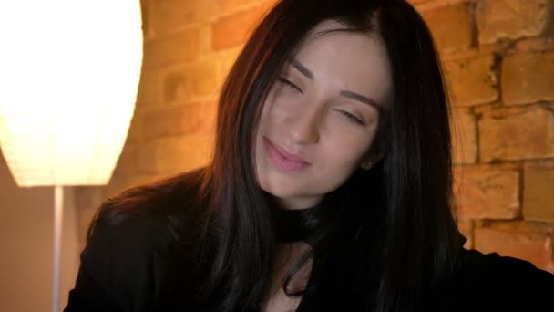 Porträt eines jungen brünetten kaukasischen Mädchens, das ruhig und bescheiden in die Kamera in häuslicher Atmosphäre blickt. — Stockvideo
