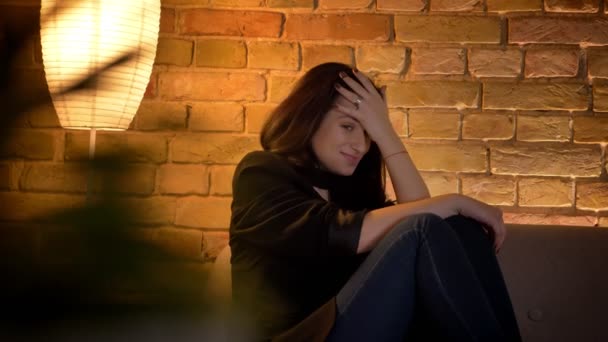 Ung brunett kaukasiska flicka sitter på soffan tittar skräck film och gömmer sig för hand i mysiga hem atmosfär. — Stockvideo