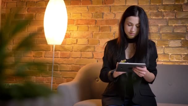 Jonge brunette Kaukasisch meisje dat met Tablet werkt aandachtig en tonend zijn horizontaal groen scherm aan camera in huis atmosfeer. — Stockvideo