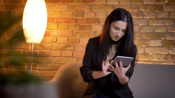 Jovem morena caucasiana trabalhando com tablet atentamente e mostrando sua tela verde vertical para câmera em atmosfera doméstica . — Vídeo de Stock