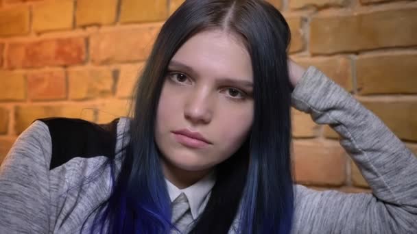 Syuting jarak dekat dari perempuan muda yang menarik kaukasia dengan rambut dicat miring di tangan dan melihat lurus ke kamera — Stok Video