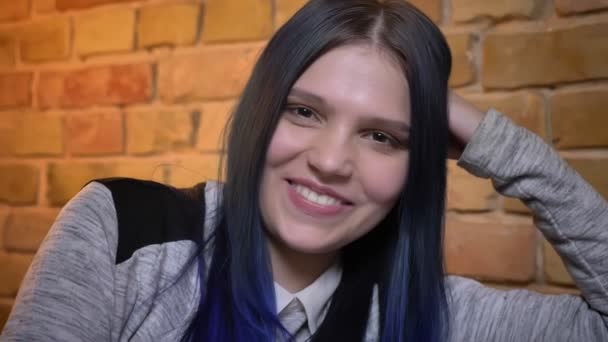 Closeup shoot of young pretty caucasian hipster female with dyed hair leaning on hand smiling and looking straight at camera — Stock Video