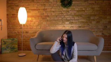 Genç çekici beyaz hipster kadın telefon gülümseyen ve keyifli evde kapalı yerde otururken mutlu gülerek konuşurken çekim çekim