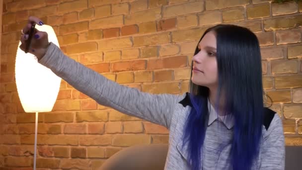 Telefonda selfie 'ler alarak genç çekici beyaz hipster kadın closeup ateş ve kamera önünde rahat ev kapalı ciouch oturan poz — Stok video