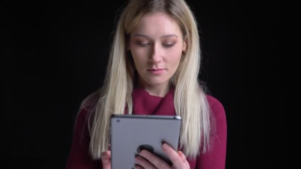 Närbild skjuta av unga vackra kaukasiska kvinnliga använder tabletten sedan titta på kamera med bakgrund isolerad på svart — Stockvideo