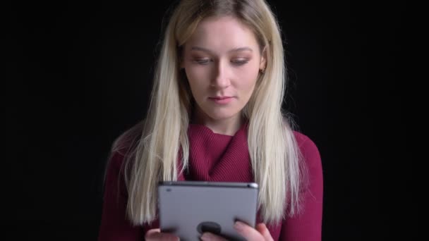 Съемки крупным планом молодой довольно белой женщины с помощью планшета перед камерой — стоковое видео