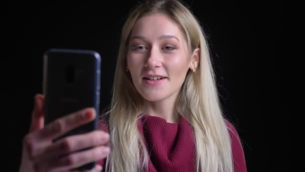Zbliżenie strzelać z młody piękny kaukaski dziewczyna z długo Blondynka włosy mający a wideo rozmowa uśmiechnięty machając Hello — Wideo stockowe