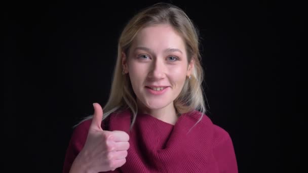 Closeup shoot of pretty caucasian female lsmiling and showing a thumb up while looking at camera — Stock Video
