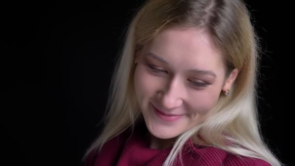 Крупним планом знімок молодої чарівної білої жінки з світлим волоссям сором'язливо і посміхається дивлячись на камеру — стокове відео