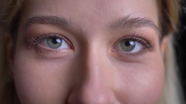 Gros plan tige de jeune visage féminin caucasien attrayant avec les yeux bleus regardant droit sur la caméra avec expression faciale souriante — Video