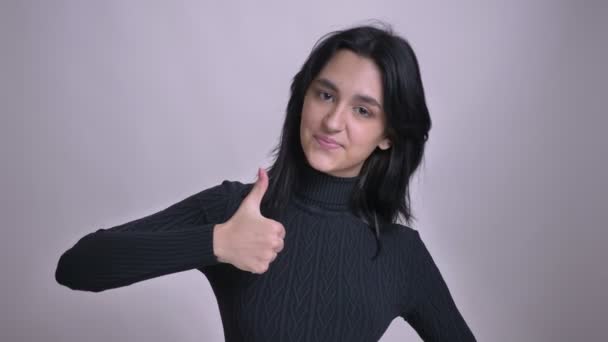 Closeup střílet z mladých krásných kavkazské černé vlasy žena ukazuje palcem a usmíval se při pohledu na fotoaparát — Stock video