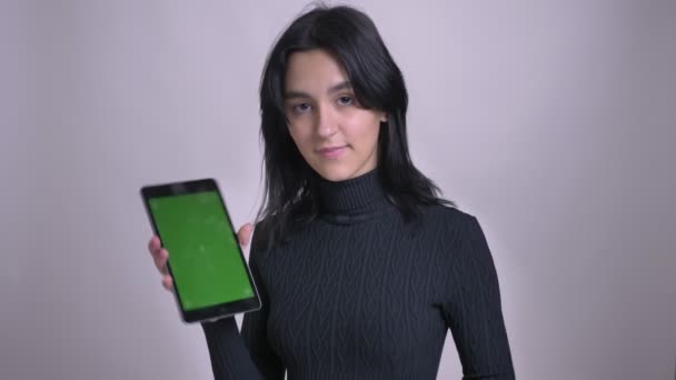 Closeup portrait of young pretty caucasian black haired female using the tablet and showing green screen to camera — Stock Video