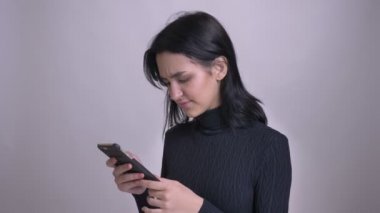 Portre genç çekici beyaz kadın sonra kameraya bakıyor ve gülümsüyor web sörf telefon kullanarak ateş