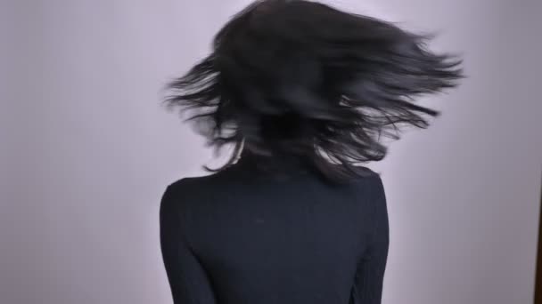 Nahaufnahme einer jungen hübschen kaukasischen Frau, die sich umdreht und ihre Haare in der Luft flattern lässt, lächelnd in die Kamera blickt — Stockvideo