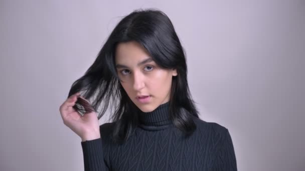 Nahaufnahme einer jungen hübschen kaukasischen Frau, die selbstbewusst und verführerisch mit ihren Haaren spielt und in die Kamera schaut — Stockvideo