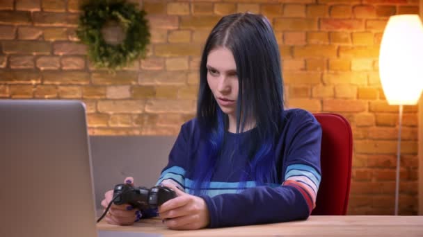 Primer plano vista recta de la joven adolescente video blogger jugando videojuegos en la computadora portátil y perdiendo enojo y disgusto en el interior — Vídeos de Stock