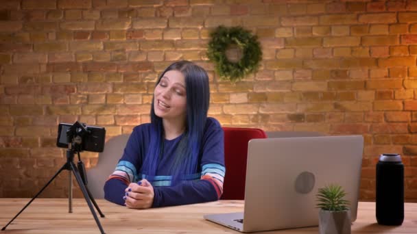 Sesión de primer plano de la joven atractiva mujer video blogger streaming en vivo hablando por teléfono usando la computadora portátil en el interior — Vídeos de Stock