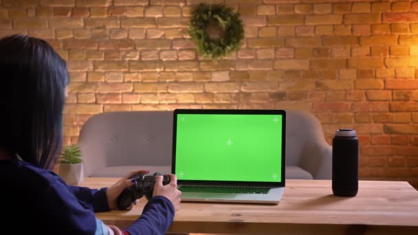 Крупним планом знімок молодої привабливої жінки відео блогер грає в відеоігри, використовуючи консоль на ноутбуці з зеленим хромовим екраном — стокове відео
