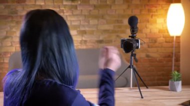 Arkadan görünüş canlı ve el süre kamera konuşurken genç çekici beyaz kadın video Blogger