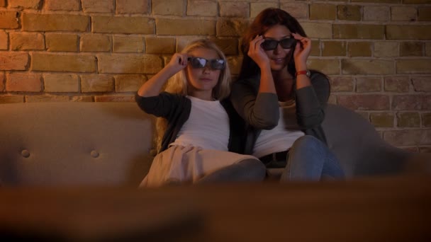Съемки крупным планом молодой белой женщины и ее маленькой дочери, смотрящей телевизор в 3D-очках дома — стоковое видео