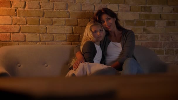 Primo piano ripresa di giovane donna caucasica e la sua dolce bambina guardando una TV insieme abbracciando e sorridendo — Video Stock