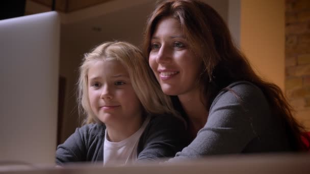 Σουτ closeup των νέων ευτυχισμένη μητέρα και το μικρό όμορφο κορίτσι βλέποντας μια ταινία μαζί και να αγκαλιάζονται στο φιλόξενο σπίτι — Αρχείο Βίντεο