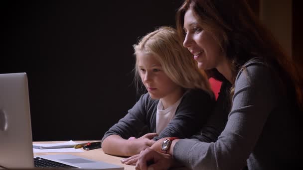 Närbild porträtt av unga kaukasiska mor och hennes lilla vackra flicka titta på en film på den bärbara datorn och skrattar — Stockvideo