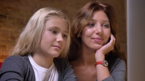 Крупним планом портрет молодої матері і її дочки дивитися відео на ноутбук в затишному будинку в приміщенні — стокове відео