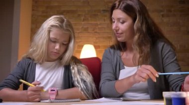 Portre çekimi genç beyaz anne küçük güzel kızı ile konuşmak ve yavaşça kızlar saç rahat ev tamir ev ödevi yardım