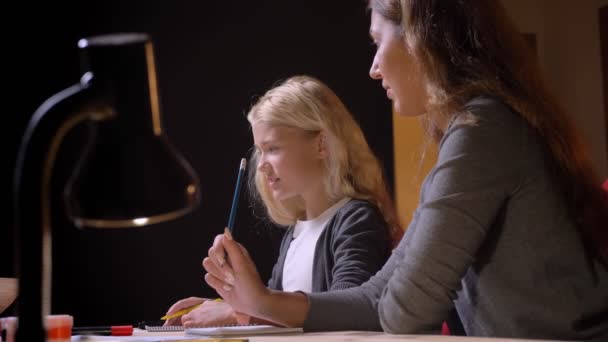 Nahaufnahme Shooting von kleinen hübschen blonden Mädchen Beantwortung ihrer Mutter algebraische Frage mit Hintergrund isoliert auf schwarz — Stockvideo