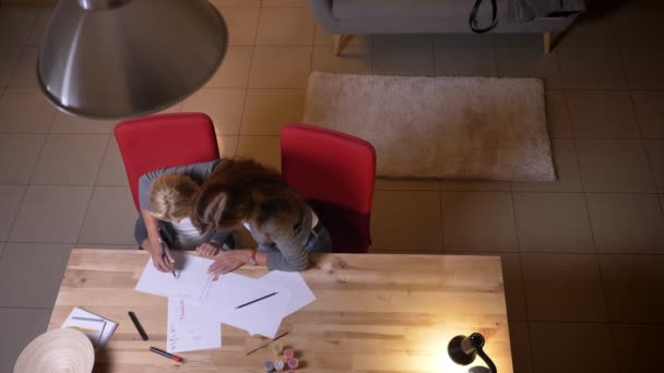 Primer plano retrato superior de la joven mujer caucásica y su pequeña hija bonita pasar tiempo juntos. Madre enseñando a una chica a dibujar — Vídeos de Stock