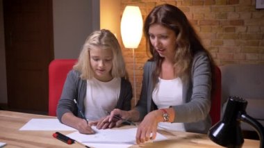 Genç anne ve küçük güzel kızı bir tic tac toe oyun kağıt üzerinde birlikte kapalı rahat evde oynamak portre portre