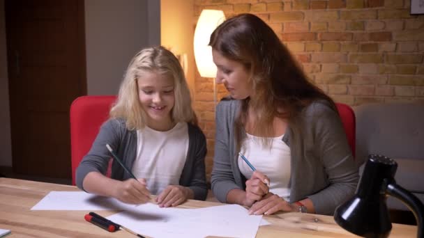 Close-up opnamen van de jonge moeder en haar kleine mooie dochter tekening glimlachen en lachen terwijl het besteden van tijd samen — Stockvideo