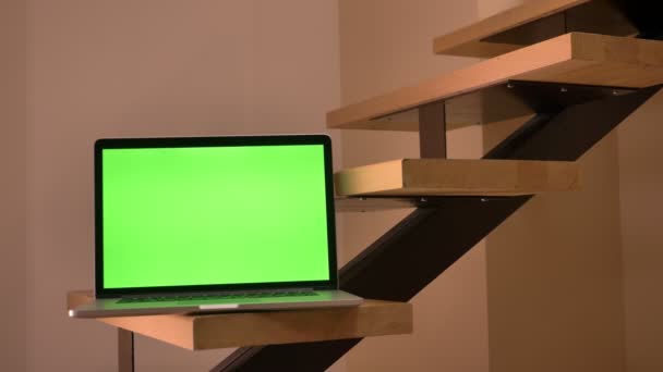 Крупним планом знімок зеленого екрану ноутбука, що лежить на сходах в офісі в приміщенні — стокове відео