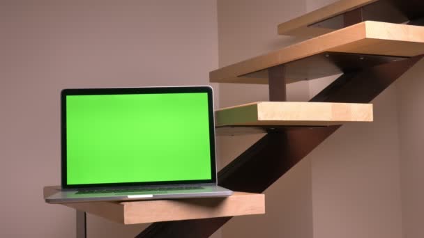 Closeup σουτ του φορητού υπολογιστή με οθόνη πράσινο χρώμα που βρίσκεται στα σκαλοπάτια στο εσωτερικό στην μπροστινή όψη το γραφείο — Αρχείο Βίντεο