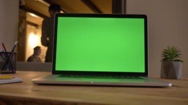 Closeup çekim ofiste masa üzerinde kapalı yalan arka plan üzerinde etkileşim çalışanı olan dizüstü yeşil bir ekran