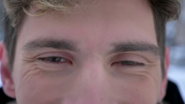 Съемка крупным планом молодого привлекательного кавказского мужского лица с карими глазами, смотрящего в камеру с улыбкой на лице — стоковое видео